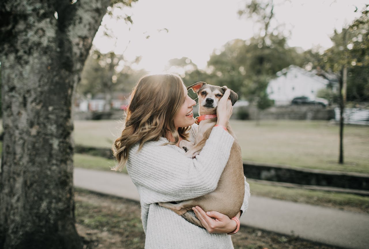 A woman carrying her dog at a public park