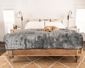 golden retriever laying down on charcoal grey short fur blanket on king size bed